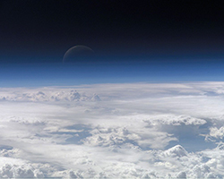 Picture of Earth's atmosphere with the crescent moon shining on the upper edge.