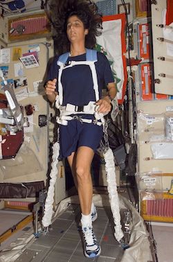 An astronaut exercising on a treadmill (chained down) in space