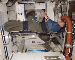 An astronaut sleeping in space (strapped in)